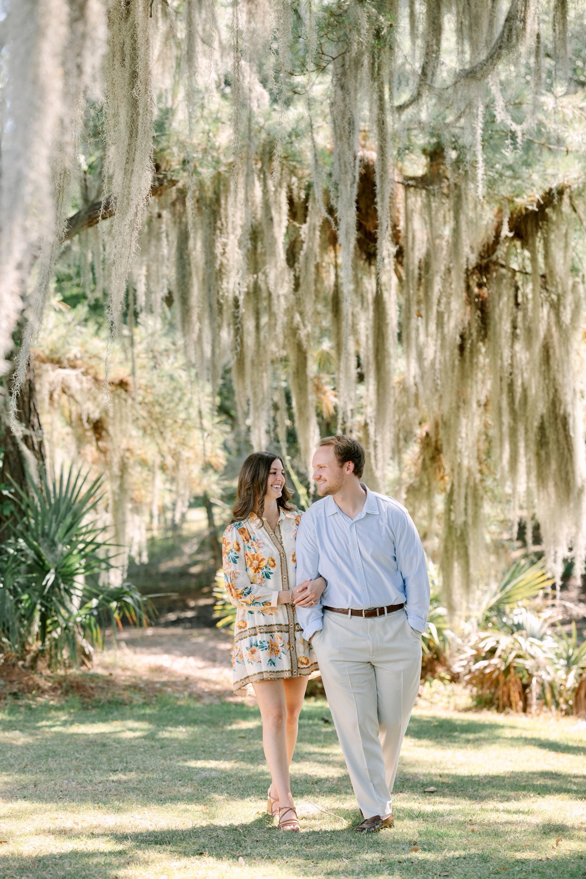 The couple walking together beneath Spanish moss